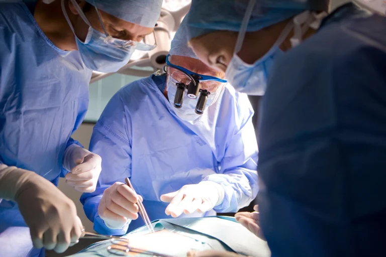 Tre kirurger udfører operation i operationsstuen, hvor kirurgisk røg kan opstå ved brug af elektrokirurgi og diatermi